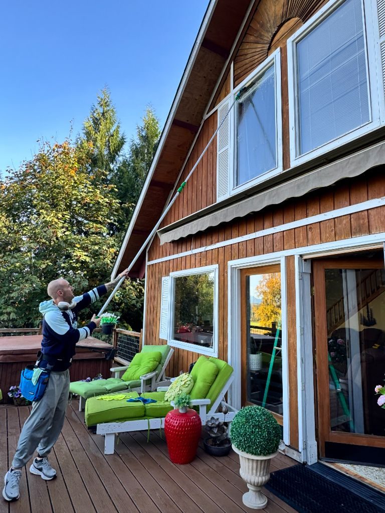 Colin of C & A Window Cleaning cleaning second-story windows on a Whatcom County home with a water-fed pole